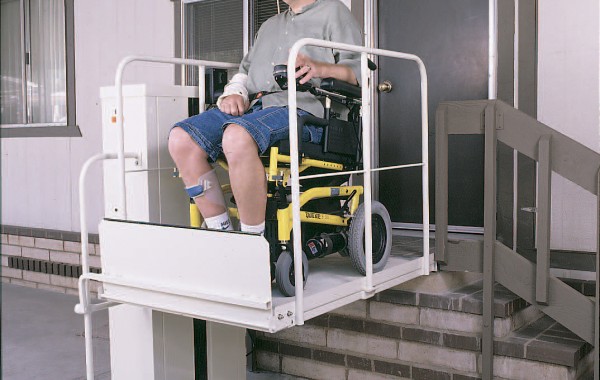 Mac's PL-50 vertical platform porch lift with a rider, available used at Electropedic